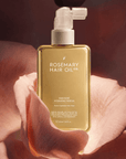 Hair Rosé Hydrating Parfum Mist. Rosemary hair oil bottle with pump and pink roses on a beige background. “Luxury hair perfume mist designed to hydrate dry hair and add a soft floral scent.