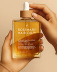 Rosemary hair oil bottle held by a hand against a beige background. Lightweight rosemary scalp oil for healthier hair growth and balanced scalp care
