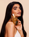 Woman holding a bottle of Rosemary Hair Oil. Rosemary hair and scalp oil formulated to support hair growth and soothe the scalp