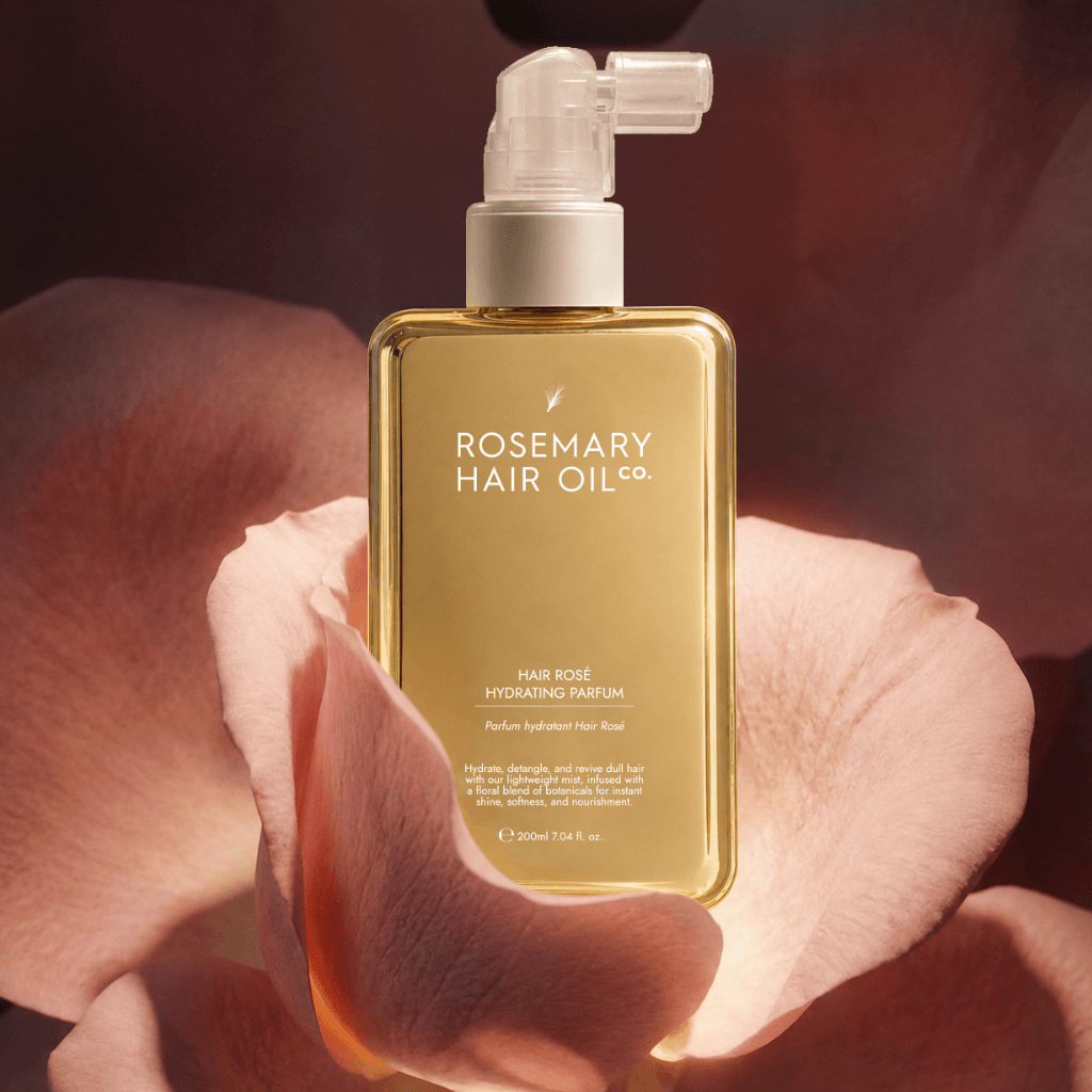 Hair Rosé Hydrating Parfum Mist. Rosemary hair oil bottle with pump and pink roses on a beige background. “Luxury hair perfume mist designed to hydrate dry hair and add a soft floral scent. 