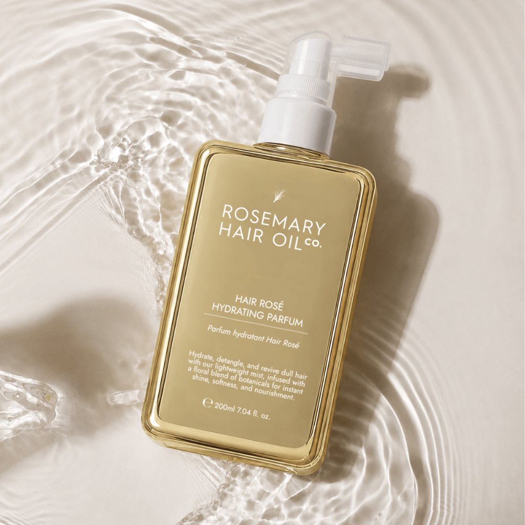 Hair Rosé Hydrating Parfum Mist. Rosemary hair oil bottle with pump and pink roses on a beige background. “Luxury hair perfume mist designed to hydrate dry hair and add a soft floral scent. 