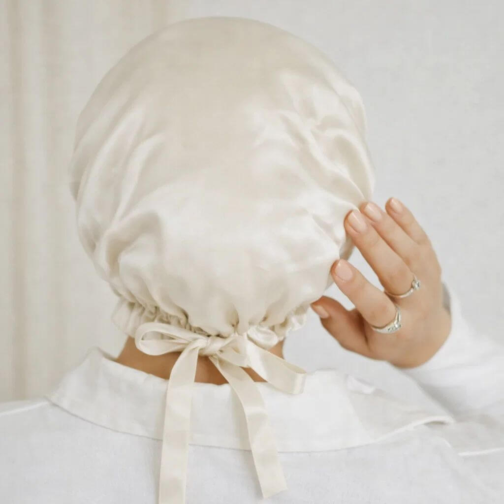 Person wearing a beige satin bonnet with a bow, Rosemary hair oil, pure silk hair bonnet, hairhalo, uk, haircare, healthy hair