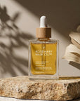 Rosemary hair oil bottle with dropper on a stone surface with natural light. Rosemary hair oil, argan, almond, bond, boost, hair growth, coconut oil, healthier, fuller-looking hair, stimulate, regrowth, hair thinning, natural, 100ml, 